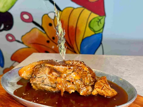 Plato de carne bañado en salsa y decorado con ajonjolí.