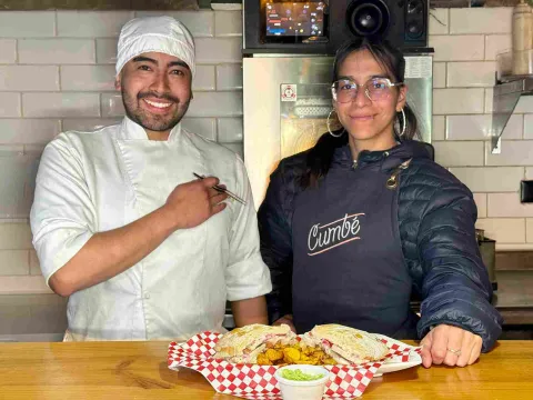 Chef y comensal presentan el sánduche de chicharrón acompañado de papas y salsa de aguacate.