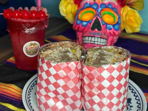  Burritos rellenos acompañados de una bebida roja y decoración alusiva a la cultura mexicana.