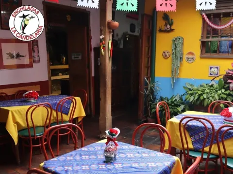 Patio interior de Enchiladas La Candelaria, decorado con colores vivos, mesas con manteles mexicanos, plantas y motivos tradicionales.