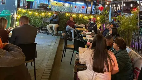 Espacio al aire libre de La Berraquera, con comensales compartiendo en un ambiente acogedor, rodeado de vegetación e iluminación cálida.