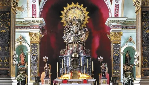 El altar mayor de la Iglesia del Voto Nacional destaca por su rica ornamentación dorada, esculturas religiosas y el imponente Sagrado Corazón de Jesús, rodeado de detalles decorativos que realzan la solemnidad del templo.