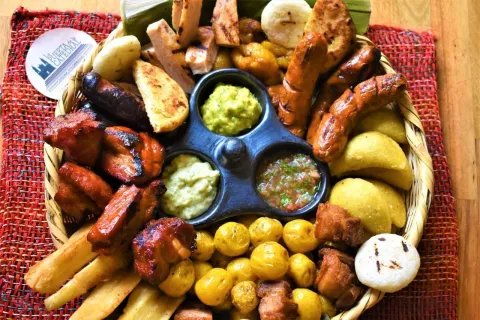 Picada colombiana con carnes, chorizos, arepas, papas, plátano y salsas.