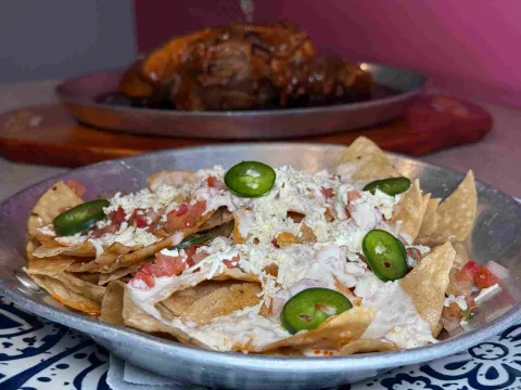  Nachos con crema, queso, pico de gallo y rodajas de jalapeño.