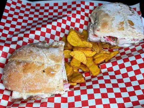 Sánduches de chicharrón servidos con papas crocantes sobre papel de cuadros rojos y blancos.