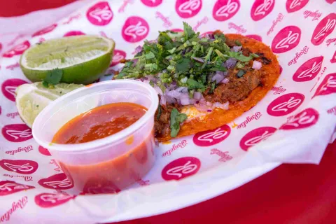 Taco de birria con queso, cebolla, cilantro y salsa picante.