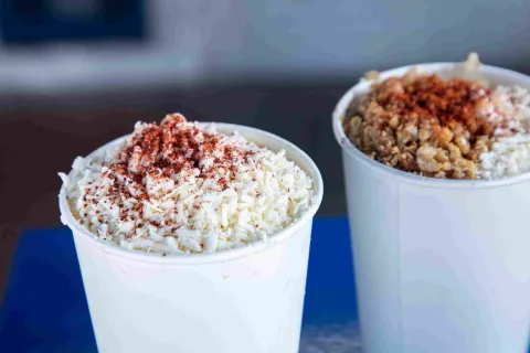 Vasos de esquites preparados con queso y chile en polvo.