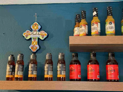 Variedad de salsas picantes y productos mexicanos exhibidos en estanterías decoradas.