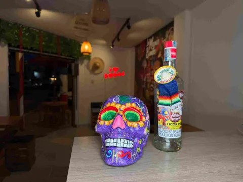 Calavera decorativa junto a una botella de licor en un ambiente de inspiración mexicana.