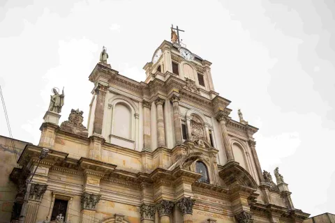  La imponente fachada de la Basílica Menor del Voto Nacional destaca por su arquitectura de inspiración neoclásica, sus columnas ornamentadas, esculturas religiosas y una torre central coronada por una cruz.