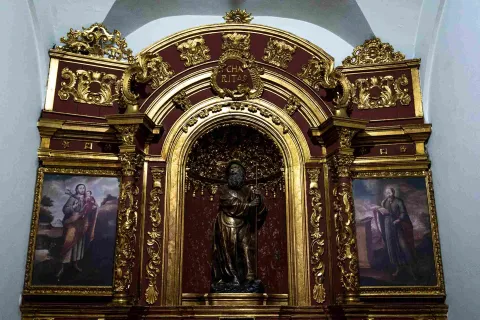 Retablo dorado de la Iglesia de San Juan de Dios, con una imagen central de un santo y pinturas religiosas enmarcadas en una ornamentada estructura barroca.