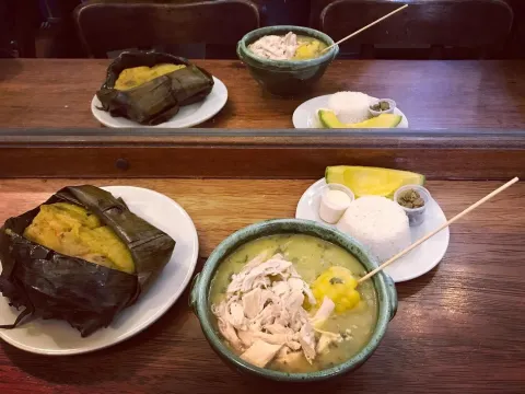 Ajiaco santafereño servido con pollo, mazorca, papa, arroz, aguacate y alcaparras.