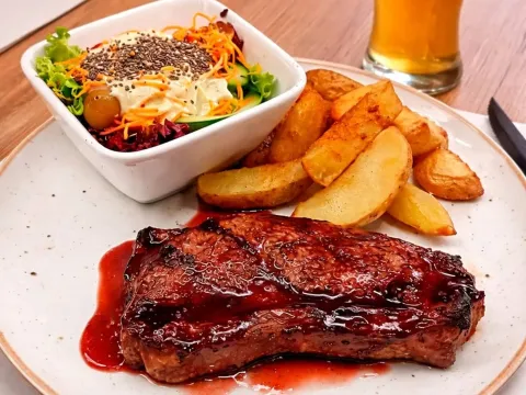 Costillas de cerdo glaseadas acompañadas de papas doradas y ensalada.