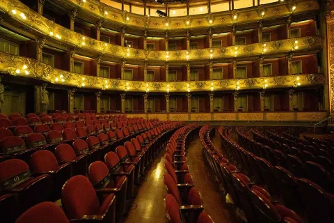 Interior del Teatro Colón de Bogotá, con su elegante arquitectura, palcos ornamentados y filas de butacas rojas.