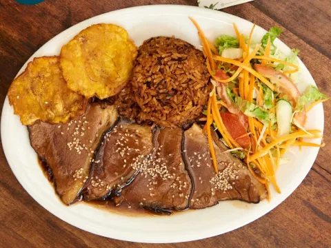  Plato de carne en salsa acompañado de arroz, patacones y ensalada fresca de lechuga, tomate, zanahoria y pepino.