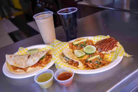 Variedad de tacos y quesadillas al pastor acompañados de salsas y bebidas.