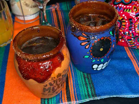  Bebidas servidas en vasos de barro decorados con motivos de calaveras mexicanas.