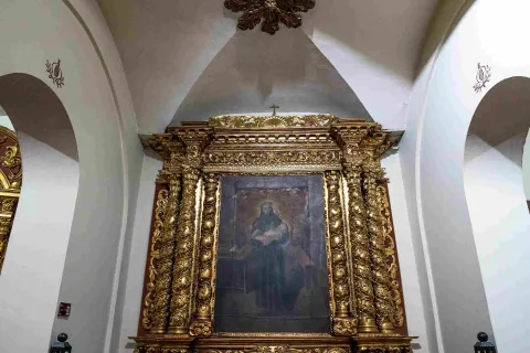 Retablo de estilo barroco con abundantes detalles dorados que enmarca una pintura religiosa en el interior de la iglesia de San Juan de Dios.