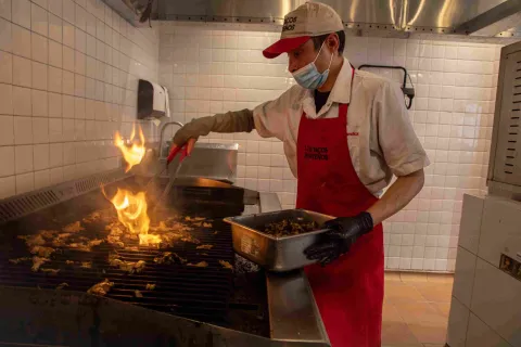 Cocinero preparando carne a la parrilla en la cocina de Los Tacos Norteños.