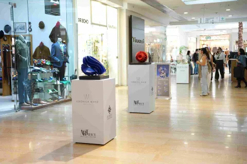 Un elegante pasillo del Centro Comercial El Retiro exhibe piezas de diseño y arte contemporáneo, creando un ambiente sofisticado entre boutiques, vitrinas y visitantes.