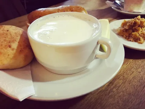 Taza de bebida caliente acompañada de pan y dulces tradicionales.