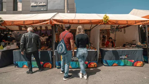 Puestos de artesanías y productos tradicionales en el Mercado de las Pulgas de Usaquén, donde visitantes recorren los coloridos stands al aire libre.