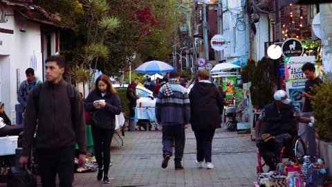 Una calle de Usaquén llena de visitantes, cafés, restaurantes y puestos de venta, en medio del ambiente tradicional y animado del sector.