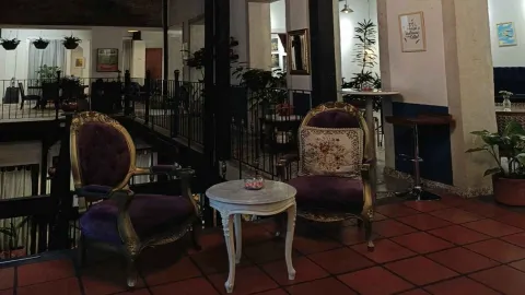 Rincón de descanso en el segundo piso con sillones de terciopelo morado y pequeña mesa auxiliar blanca. 