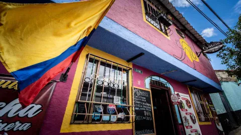 Vista exterior de la colorida fachada del restaurante, destacando la bandera nacional y el menú de pizarra en la entrada.