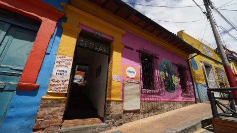 Fachada colorida del gastrobar que presenta un mural artístico y el menú en la entrada.