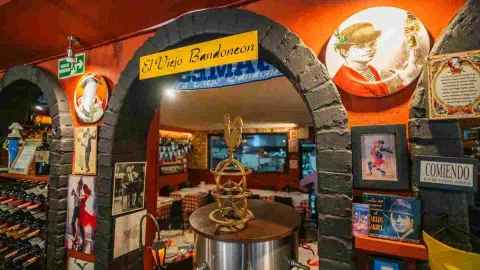 Arco de piedra decorado con fotos vintage de tango, botellas de vino y letrero de El Viejo Bandoneón.