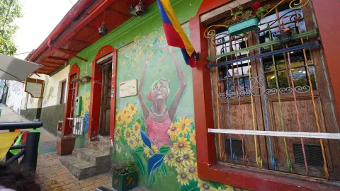 Entrada del restaurante Peri Peri con fachada verde y roja, gradas de piedra, mural y ventana colonial. 