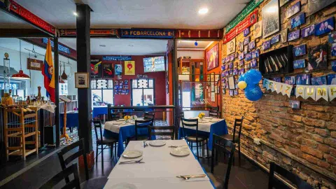 Perspectiva general del comedor interno mostrando mesas organizadas, columnas oscuras y bufandas de equipos de fútbol en la parte superior.