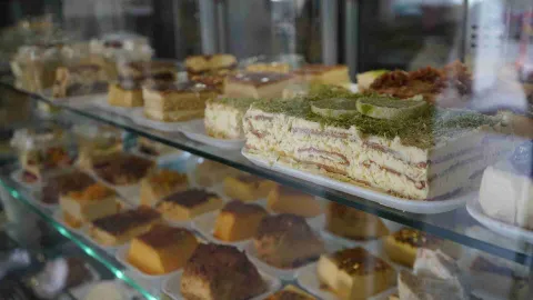 Vitrina de vidrio exhibiendo múltiples porciones de postres, bizcochos y tartas heladas en bandejas. 