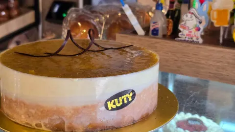 Torta helada de maracuyá con adorno de chocolate sobre una base dorada en el mostrador de Kuty. 
