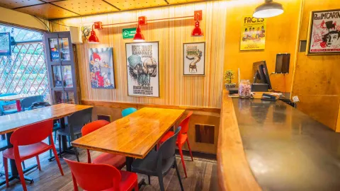  Barra de atención en madera junto a comedor interior con afiches de conciertos y lámparas de estilo industrial.