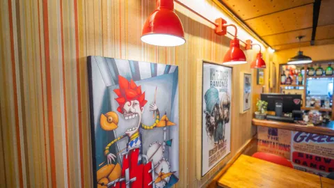 Cuadro artístico de caricatura musical en pared con papel tapiz de rayas y lámpara roja de techo encendida.