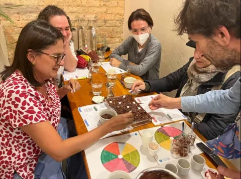 Grupo de participantes en una mesa decorando una bandeja de chocolate en un taller de cata de cacao. 