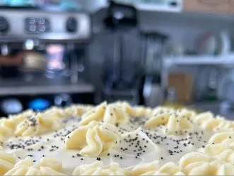 Postre cremoso decorado con crema y semillas de amapola.