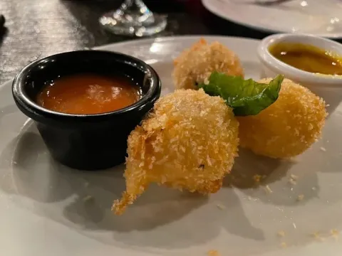 Croquetas doradas y crujientes acompañadas de salsas para degustar, decoradas con hojas de hierbabuena.