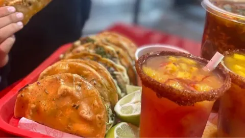 Tacos de birria servidos con bebidas preparadas y cítricos.