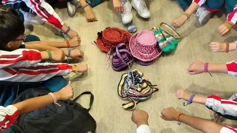  Niños y niñas comparten sus pulseras y observan bolsos y sombreros tejidos artesanalmente.