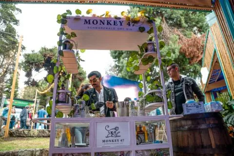  Puesto de bebidas Monkey 47 en un festival gastronómico, rodeado de visitantes.