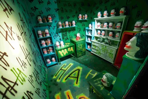 Sala temática del Museo de la Selfie en Bogotá, ambientada en tonos verdes y decorada con numerosas máscaras y cabezas de maniquí con maquillaje inspirado en el personaje del Joker. Las paredes, muebles y piso están cubiertos con grafitis que repiten expresiones de risa, creando un escenario teatral y llamativo para fotografías.