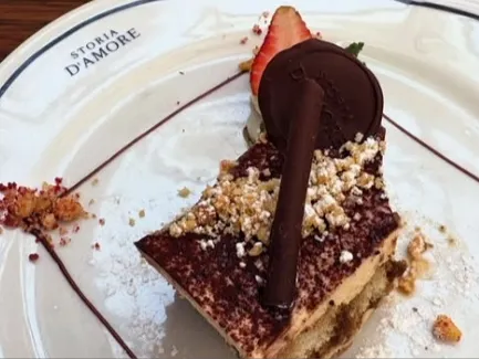 Postre de chocolate decorado con fresa, galleta y chocolate, servido en Storia D’Amore.