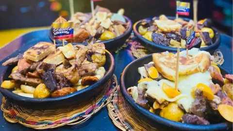 Platos de barro servidos con picadas tradicionales colombianas decorados con pequeñas banderas nacionales. 