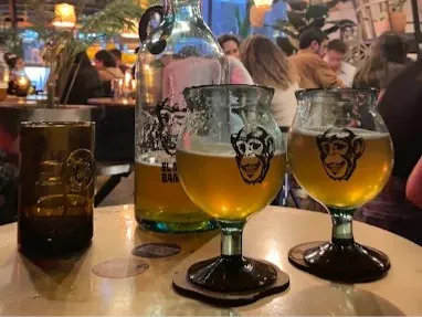Cervezas artesanales de El Mono Bandido servidas en copas y vasos, en un ambiente animado y concurrido.