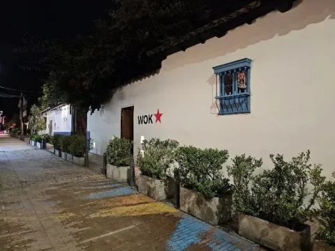 Fachada de WOK, con arquitectura colonial, jardines y el distintivo logo del restaurante.