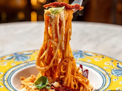 Pasta larga con salsa de tomate y queso, servida en un plato de inspiración italiana. 