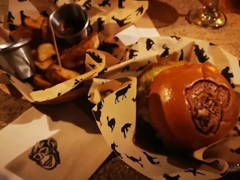 Hamburguesa acompañada de papas fritas, servida en una presentación con el característico diseño de El Mono Bandido.